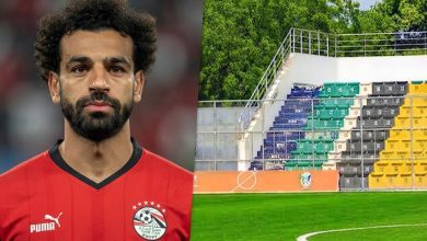 محمد صلاح بقميص منتخب مصر بجانب ملعب جوبا في جنوب السودان، مع ظهور أرضية العشب الصناعي ومدرجات الاستاد، في صورة رياضية تعبر عن غياب قائد الفراعنة عن مواجهة جنوب السودان بسبب طبيعة أرضية الملعب